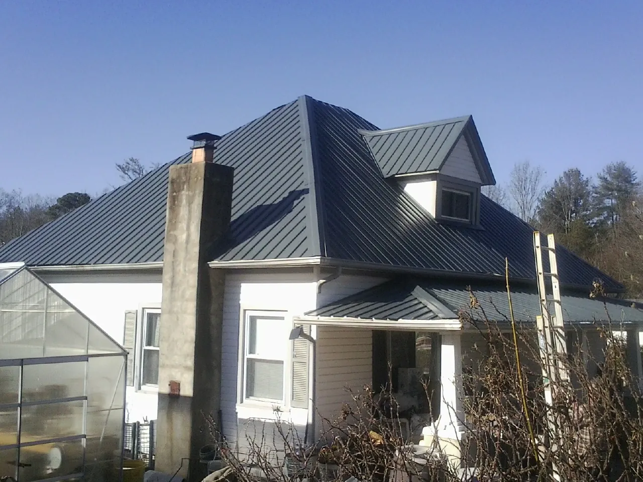 Dark blue standing seam metal roof on a white farmhouse with dormer — Slate & Tile Roof Repair by Roofing Brothers in Kingsford Heights