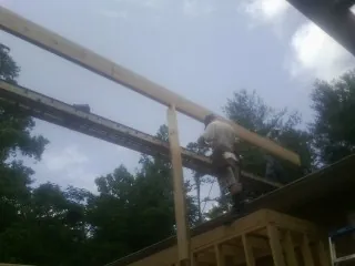 Carpenter setting a ridge beam over a new addition frame — Ice Dam Removal by Roofing Brothers in Kingsford Heights