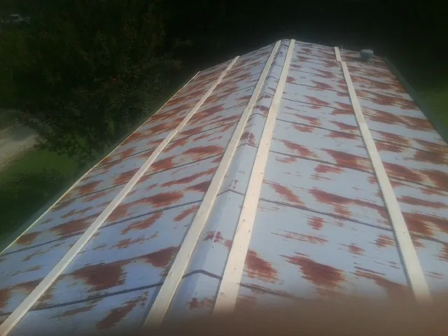 Rusted metal roof panels with new wood purlins before replacement — Storm Damage Roof Repair in Kingsford Heights by Roofing Brothers