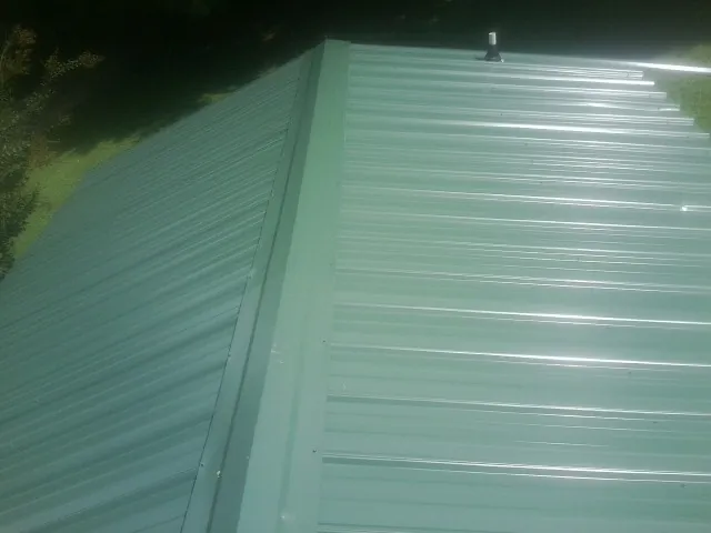 New green metal panels meeting at the ridge of a roof — Flat Roof Repair work by our crew in Kingsford Heights