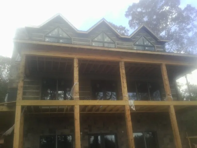 Dormers and porch framing on a large log home under construction — Roof Coating work by our crew in Kingsford Heights