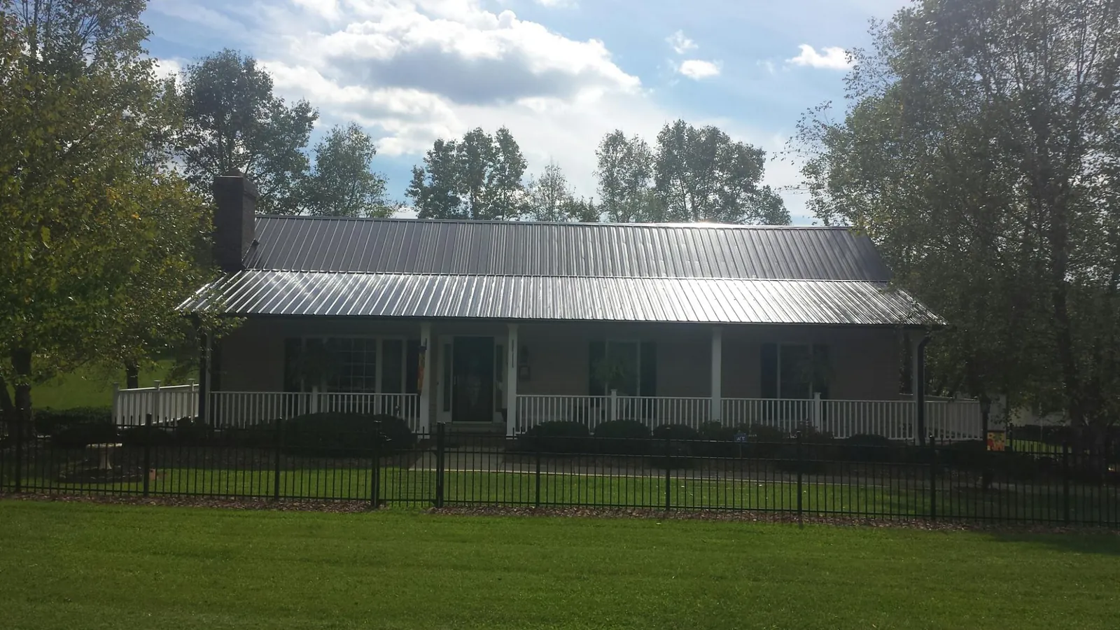 Gray metal roof on a brick ranch with a full width front porch — Gutter Guard Installation work by our crew in Kingsford Heights