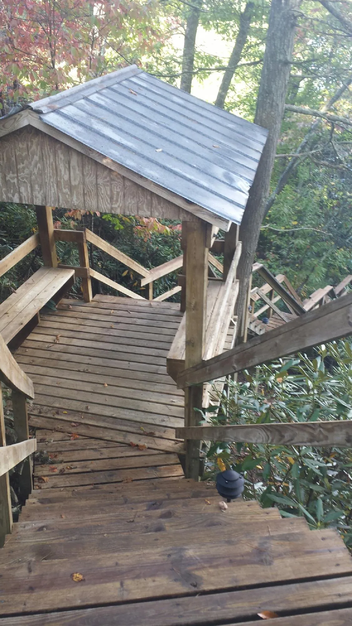 Metal roofed shelter over wooden steps on a wooded walkway — Skylight Repair & Installation work by our crew in Kingsford Heights