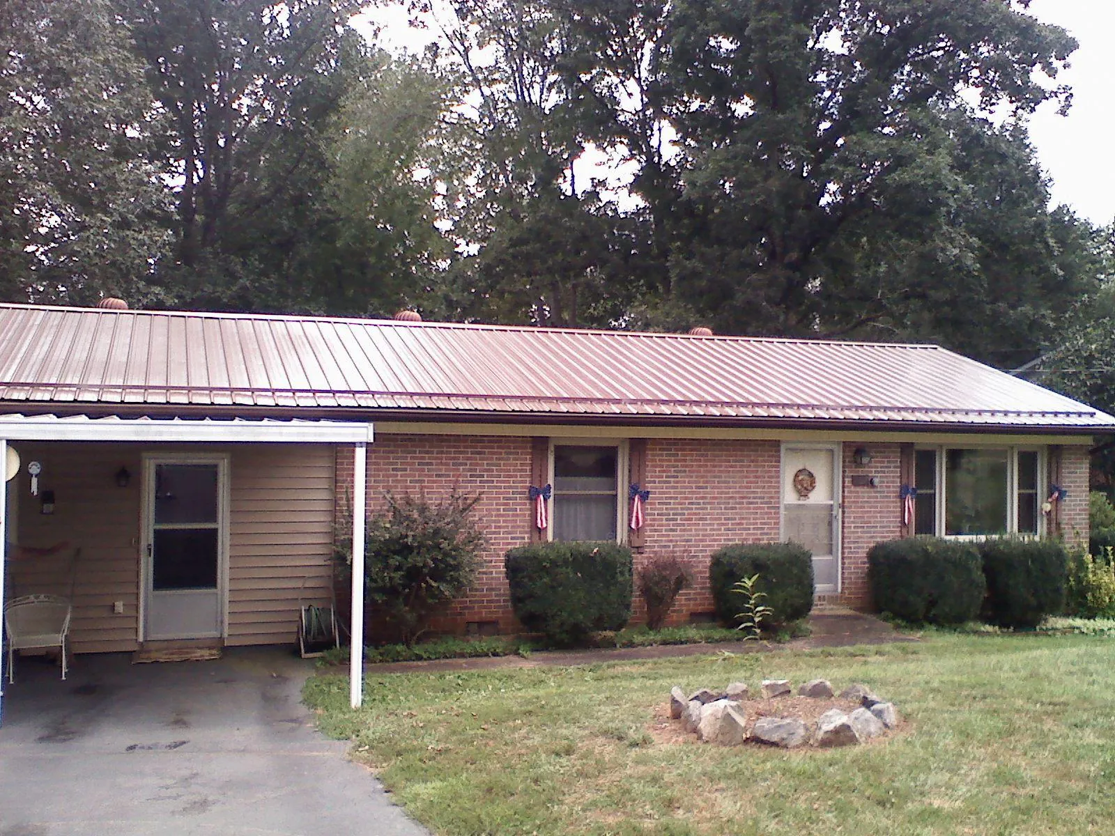 Bronze metal roof and carport on a brick ranch home — Roof Repair work by our crew in Kingsford Heights