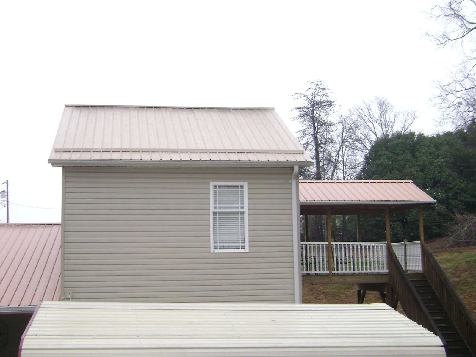 Tan metal roofs on a two story addition and attached porch, from a Roof Replacement job in Kingsford Heights