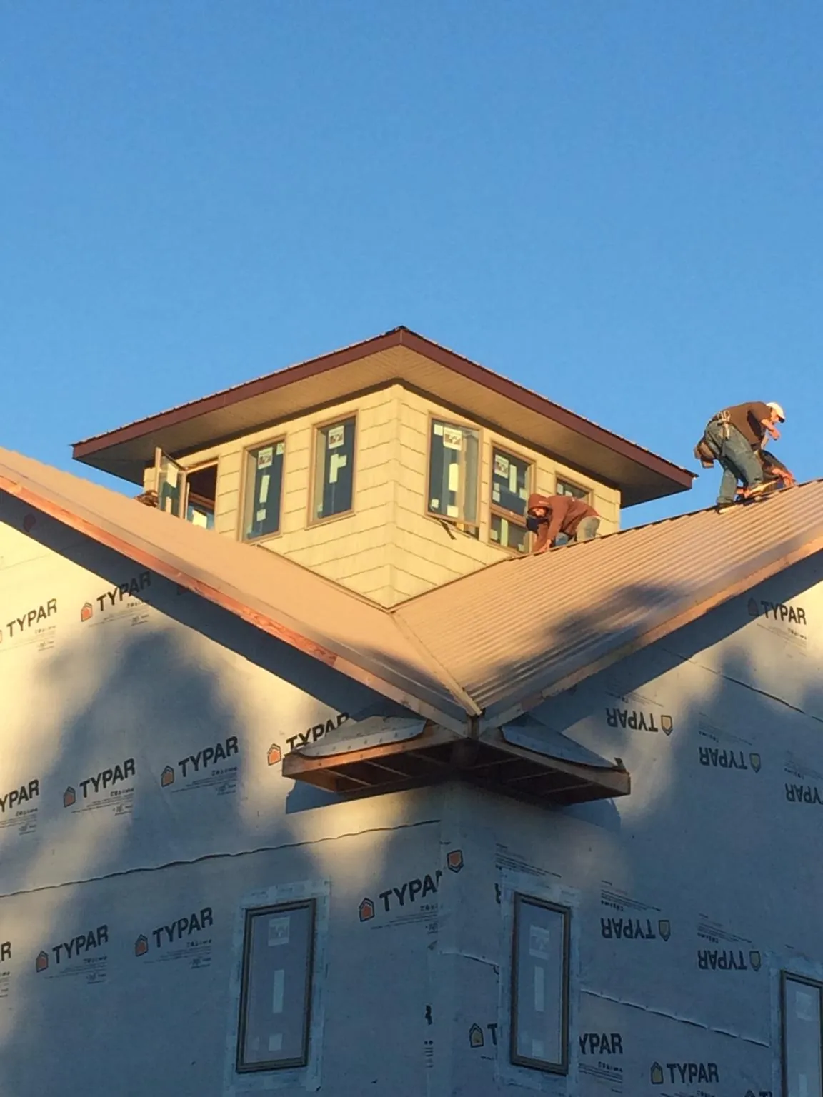 Roofers working around a rooftop cupola on a new metal roof at sunset — Roof Waterproofing in Kingsford Heights by Roofing Brothers